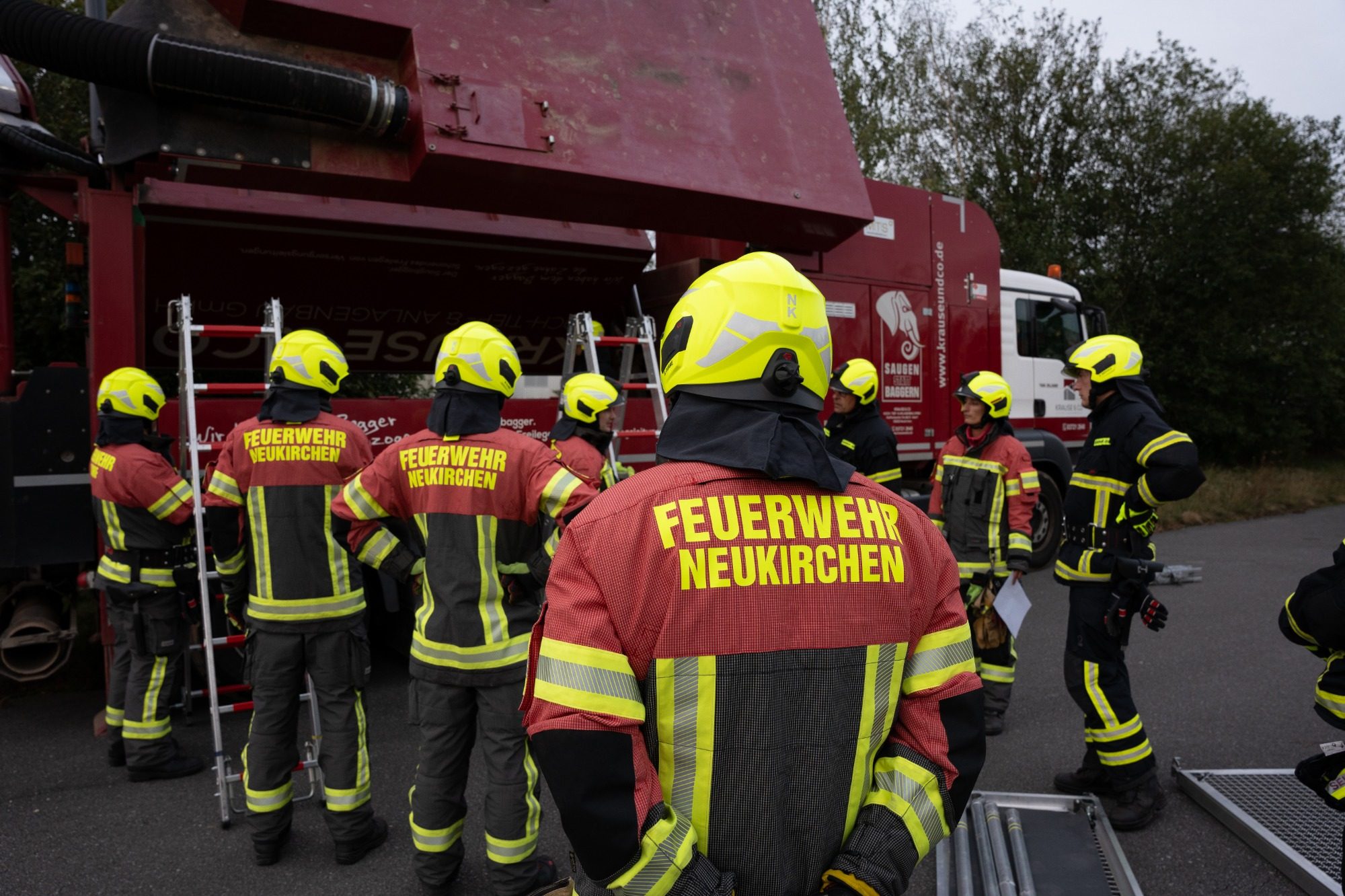 Einsatzkleidung der Feuerwehr Neukirchen Erzgebirge Feuerwehrleute in Uniform stehen vor einem Fahrzeug.