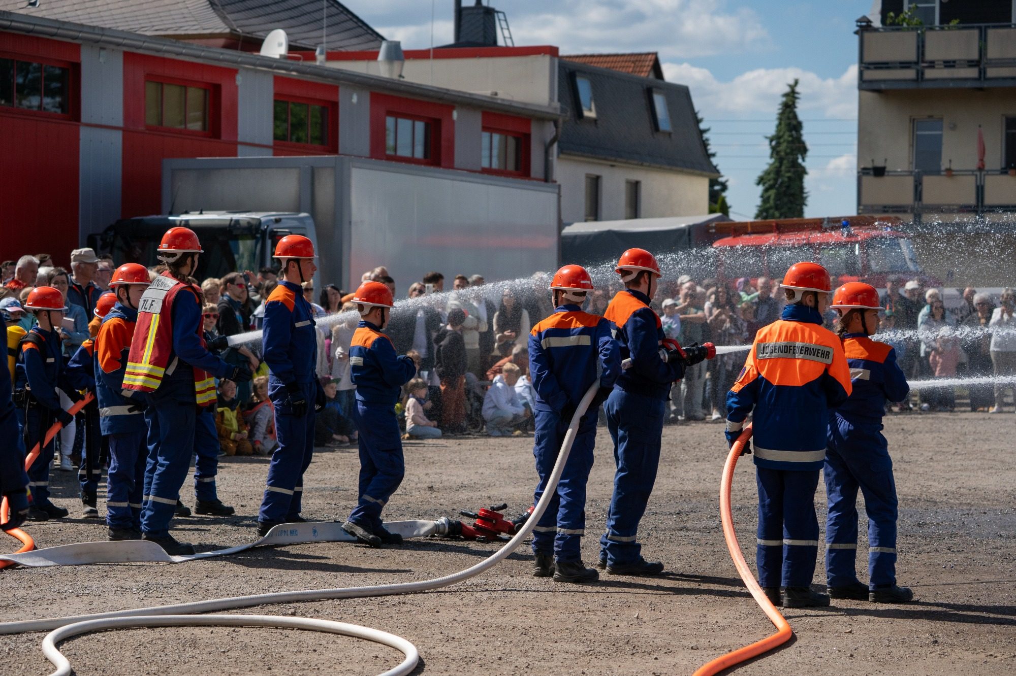 Jugendfeuerwehr der Feuerwehr Neukirchen Erzgebirge bei einer Übung Gruppierung von Jugendfeuerwehrleuten mit Schläuchen in einem Trainingsszenario.