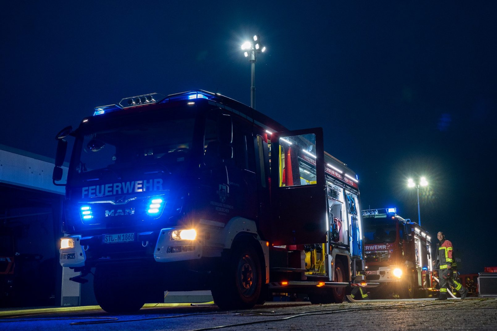 Fahrzeuge der Feuerwehr Neukirchen Erzgebirge Feuerwehrfahrzeuge der Feuerwehr Neukirchen Erzgebirge mit blauen Blinklichtern in der Nacht, beleuchtet von Scheinwerfern.